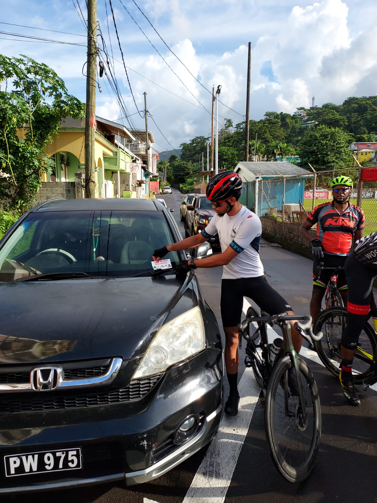 Kohath Baron, national Cyclist and member of the Dominica Cycling Association's Street Falcons cycling club, places a flyer on a vehicle as part of a safety awareness Fun Ride, which the association hosted on November 11, 2023.